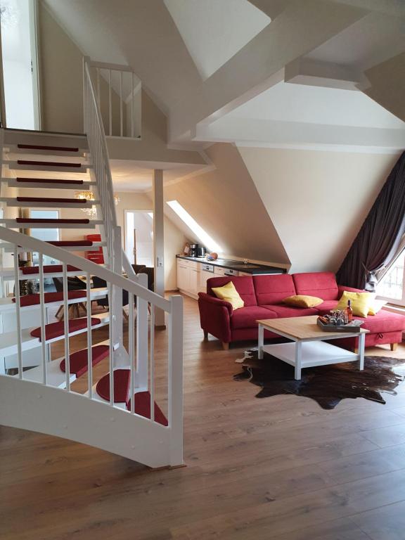 a living room with a red couch and a staircase at Ostseestrand-Apartments in Nienhagen