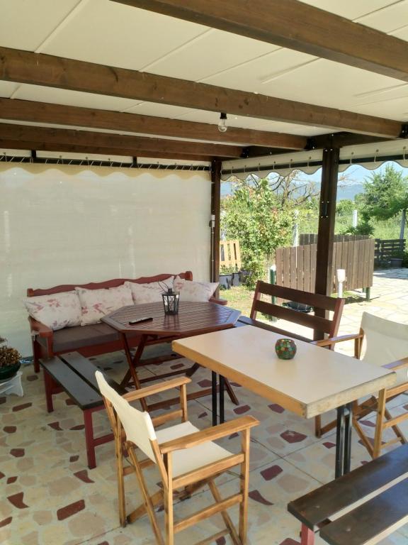 a patio with tables and chairs and a couch at Vivian Philoxenia in Néa Sampsoús