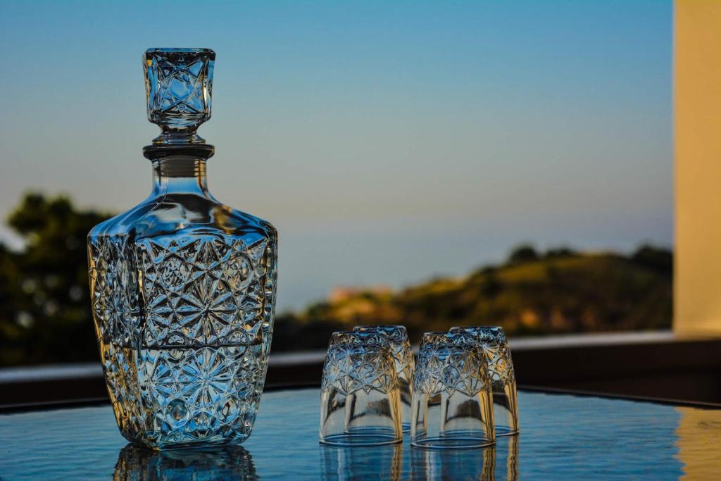 una botella de cristal azul y dos vasos en una mesa en Anthemis Apartment, en Mathés