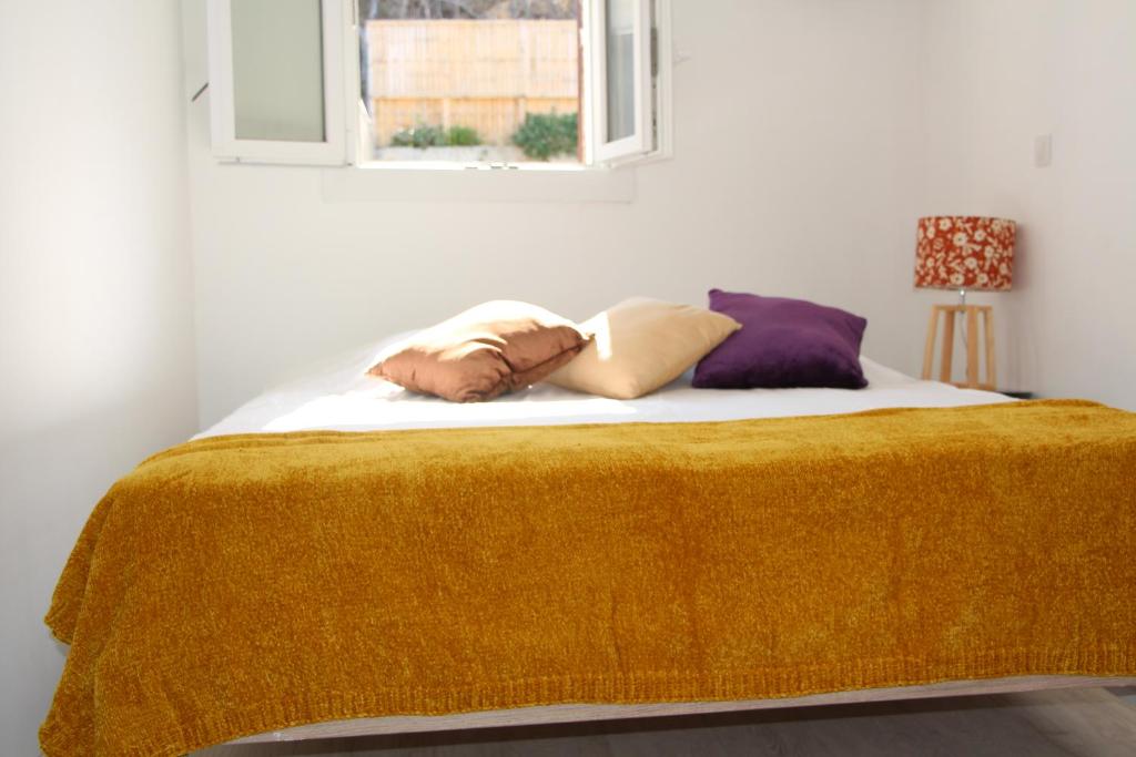 a bed with a yellow blanket and pillows on it at Charmant Cabanon aux Goudes à Marseille avec vue mer in Marseille