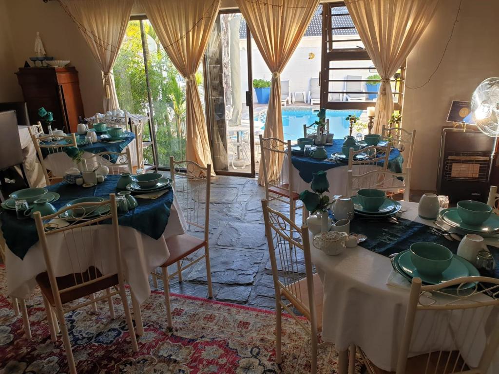 Zimmer mit Tischen und Stühlen sowie blauen und weißen Gerichten in der Unterkunft Au Plais De Langebaan at Palm Tree Villa in Langebaan