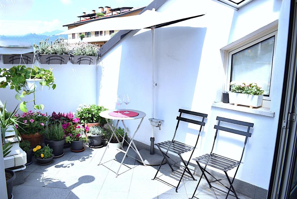 eine Terrasse mit 2 Stühlen, einem Tisch und Topfpflanzen in der Unterkunft Borgo d'Oro Loft in Bergamo
