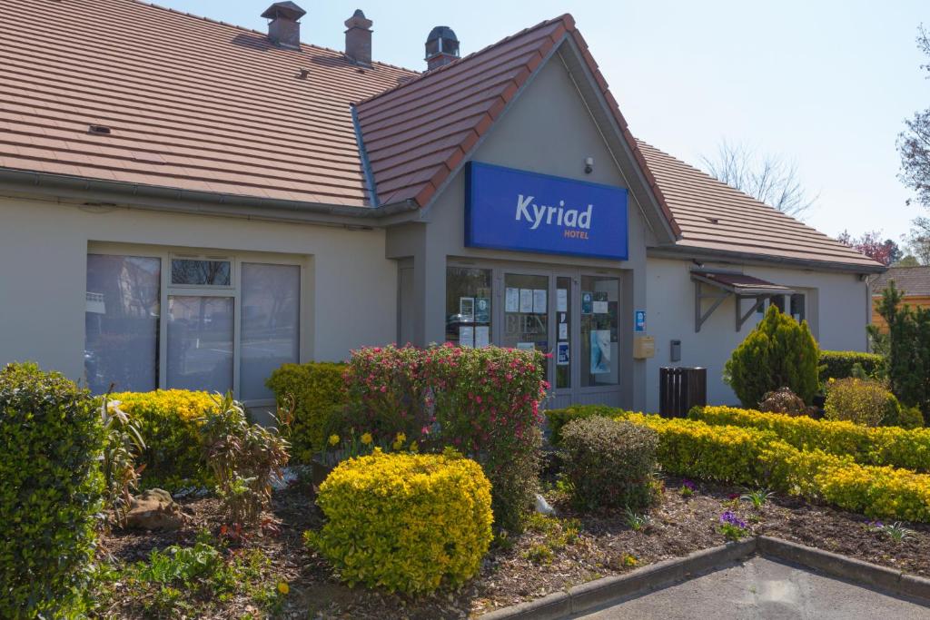 a k hybrid building with bushes in front of it at Kyriad Chantilly Sud - Luzarches in Chaumontel