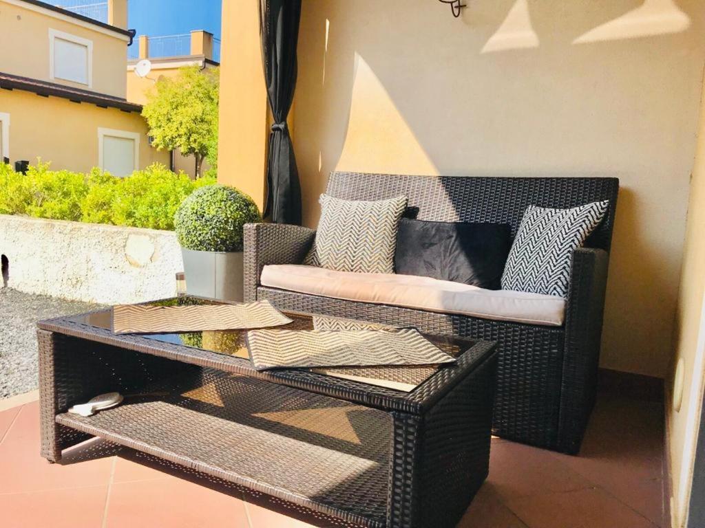 einen Korbstuhl auf einer Terrasse mit einem Tisch in der Unterkunft Pizzo Beach Club one bed Apartments in Pizzo