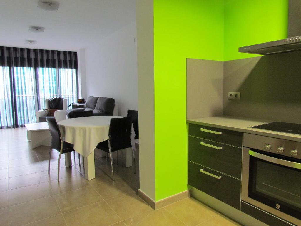cocina con paredes verdes y mesa con sillas en Apartamentos Elvira Valderrobres, en Valderrobres