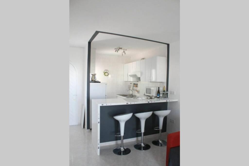 a mirror reflecting a kitchen with a counter and stools at APARTAMENTOS BINIFORCAT CB apto 52 IDEAL PLACE FOR HOLIDAY in Cala en Blanes