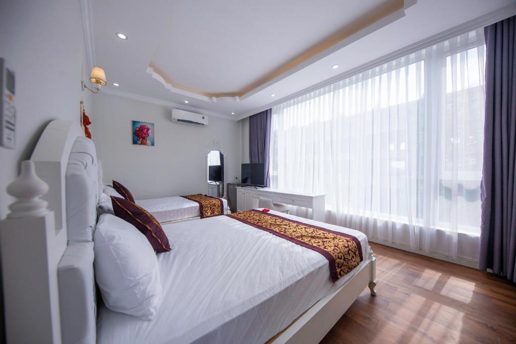a bedroom with two beds and a large window at Central Hue homestay in Hue