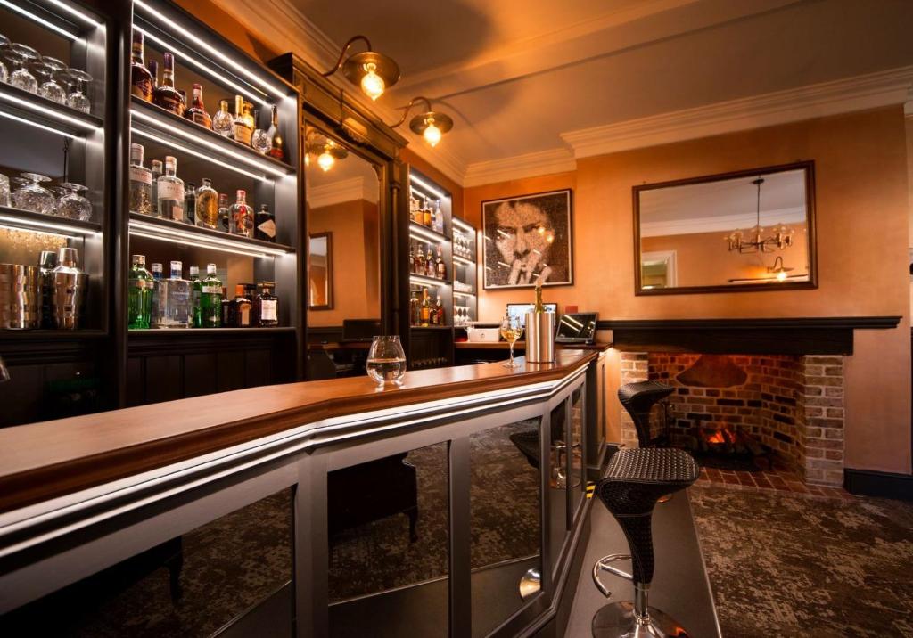 a bar with a counter and a fireplace at East Walls Hotel in Chichester