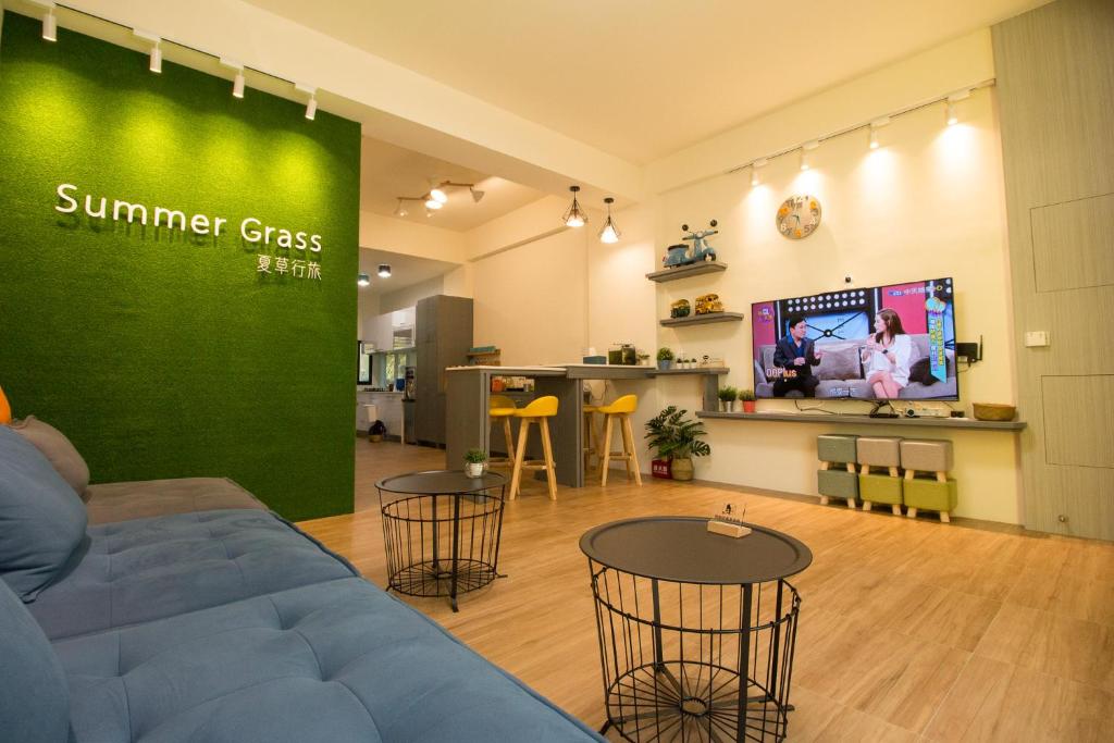 a living room with a couch and tables and a tv at Summer Grass B&B in Taitung City