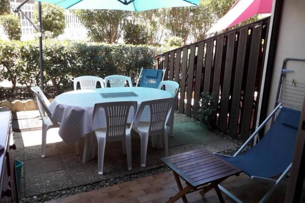 a table and chairs on a patio with an umbrella at Appartement avec jardin Gruissan in Gruissan