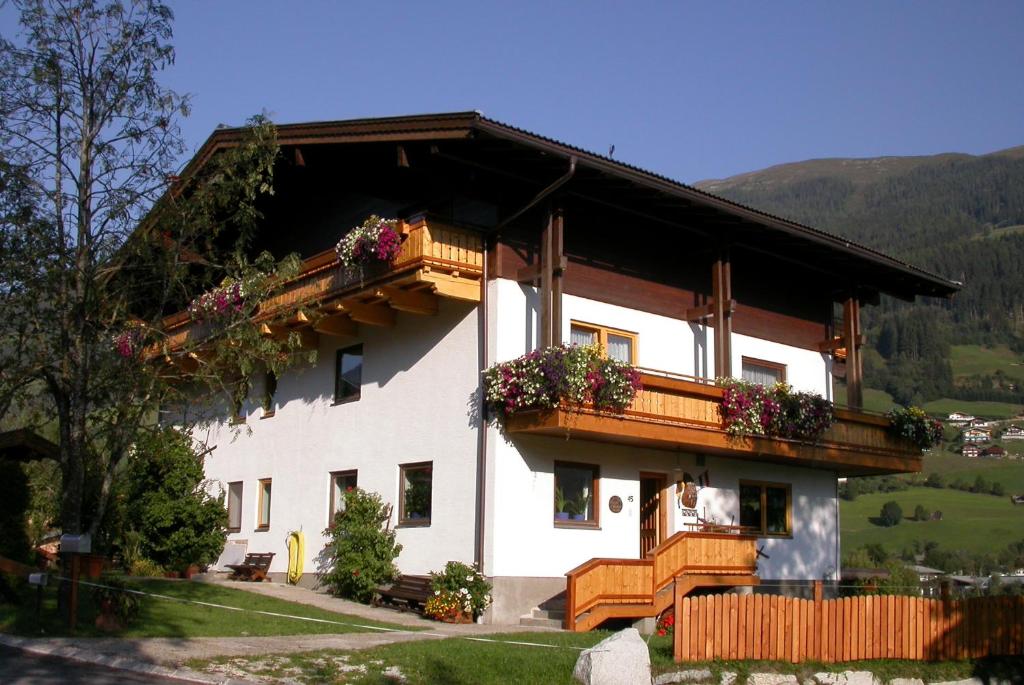 une maison avec des fleurs sur ses balcons dans l'établissement Pension Kristall, à Bramberg am Wildkogel