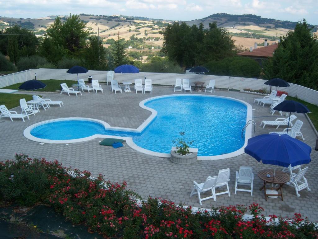 une grande piscine avec des chaises, des parasols et un avisor dans l'établissement Agriturismo Lo Sgorzolo, à Pergola