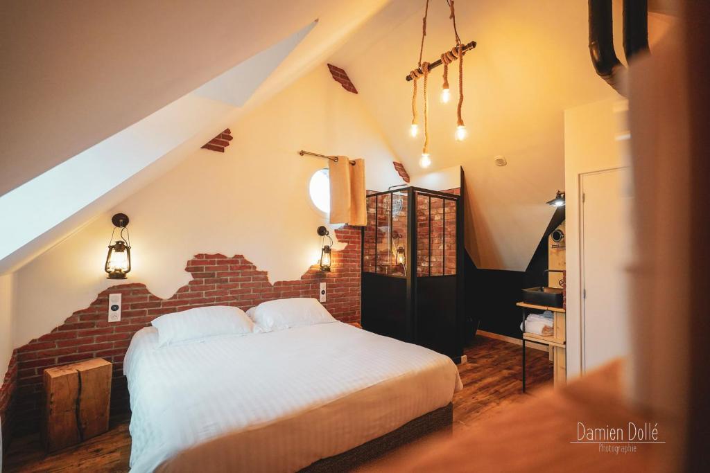 - une chambre avec un lit et un mur en briques dans l'établissement Le Saltimbanque - Auberge du Moulin, à Eaucourt-sur-Somme