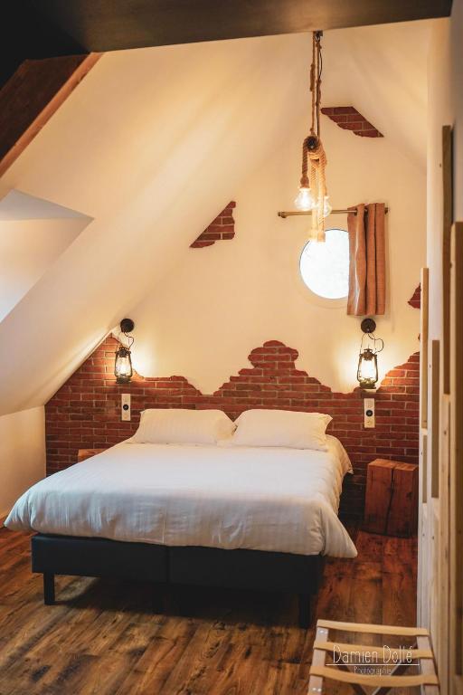 a bed in a room with a brick wall at Le Saltimbanque - Auberge du Moulin in Eaucourt-sur-Somme