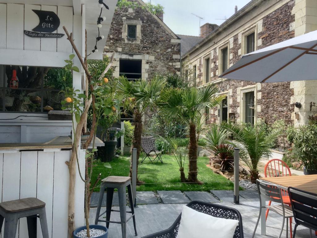 um pátio com uma mesa e cadeiras e um jardim em Le Logis des Mariniers em Chalonnes-sur-Loire