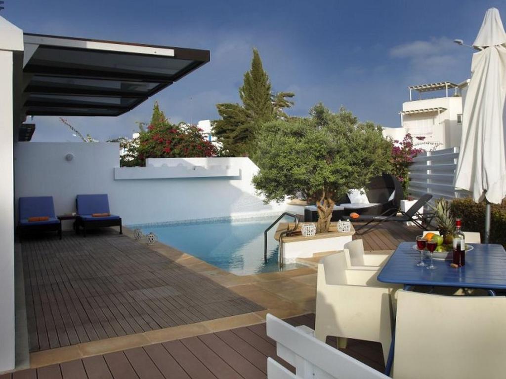 un patio con piscina, mesa y sillas en Protaras Nausicaa Villa Mykonos, en Protaras