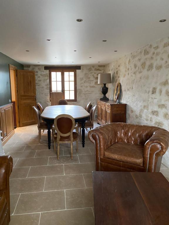 a living room with a table and leather furniture at La Maison du Caillou in Pontarmé