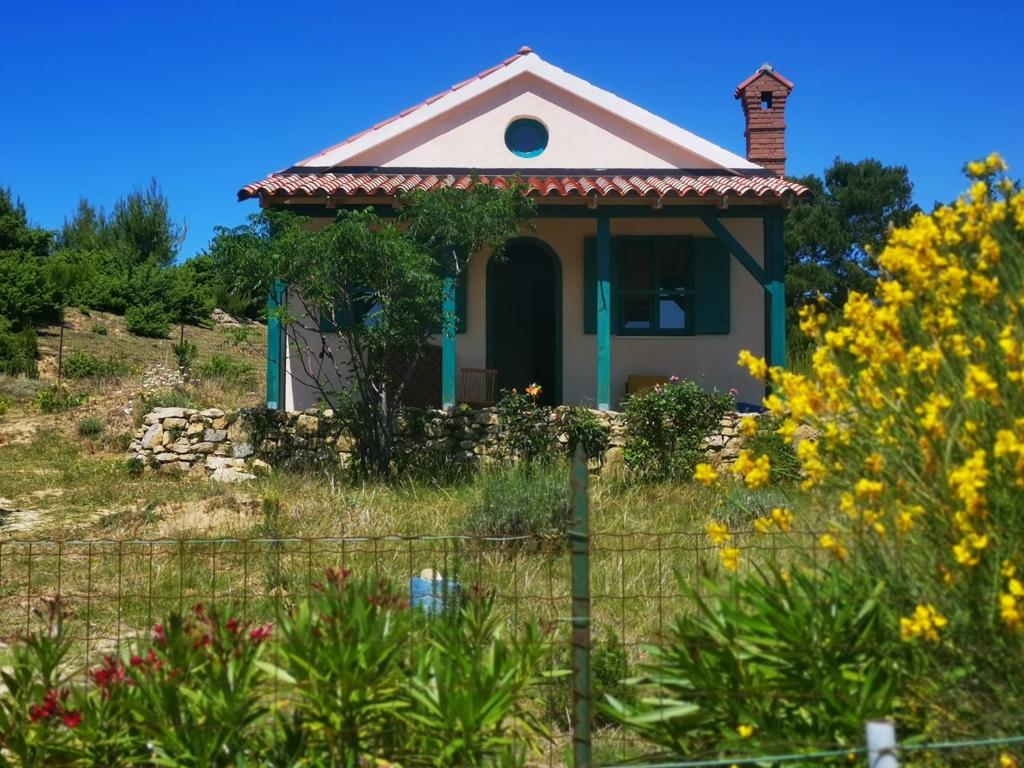 una pequeña casa en un campo con flores en Arya House en Lopar