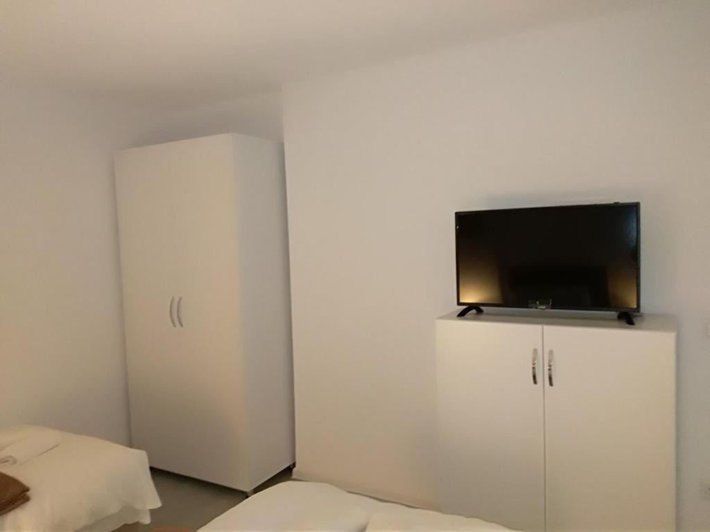 Habitación con armario blanco y TV de pantalla plana. en Apartman-Stan na dan -Stolac en Stolac