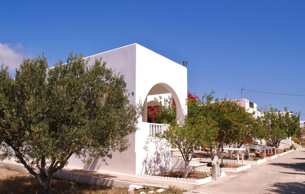 a white building with trees in front of a street at Scarpantos in Amoopi