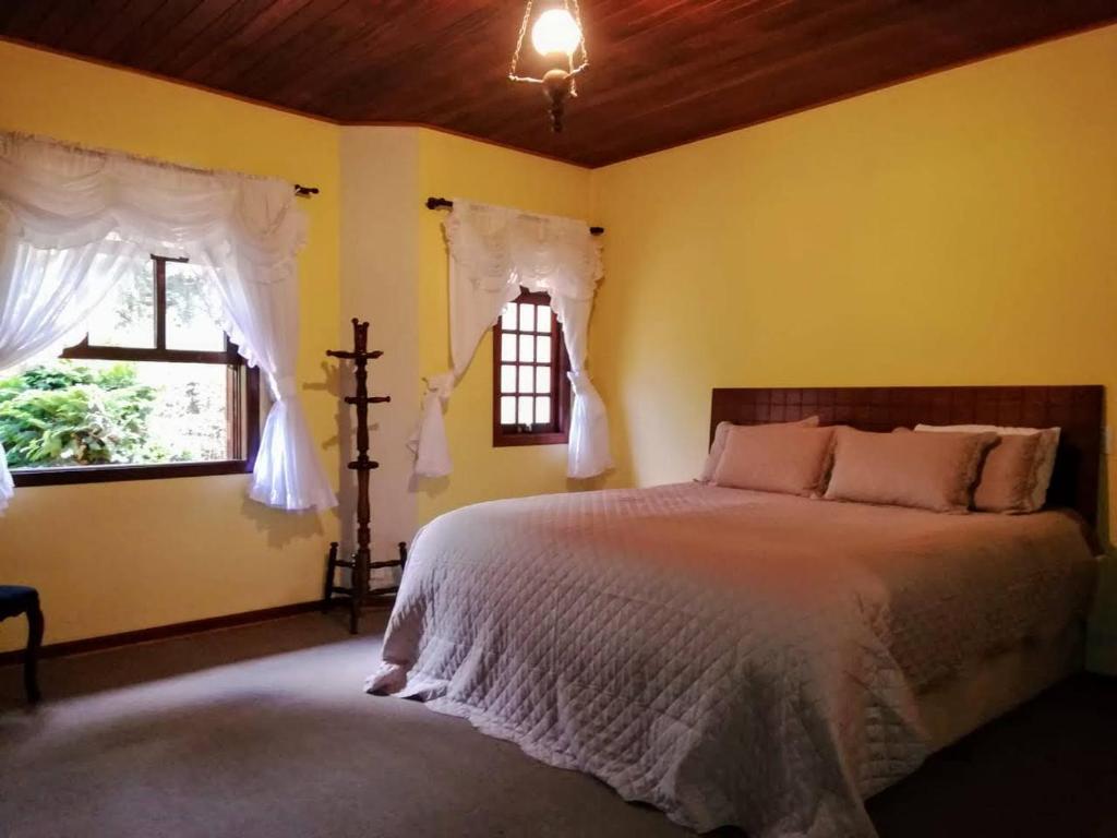a bedroom with a bed and two windows at Pequeno Paraiso in Campos do Jordão