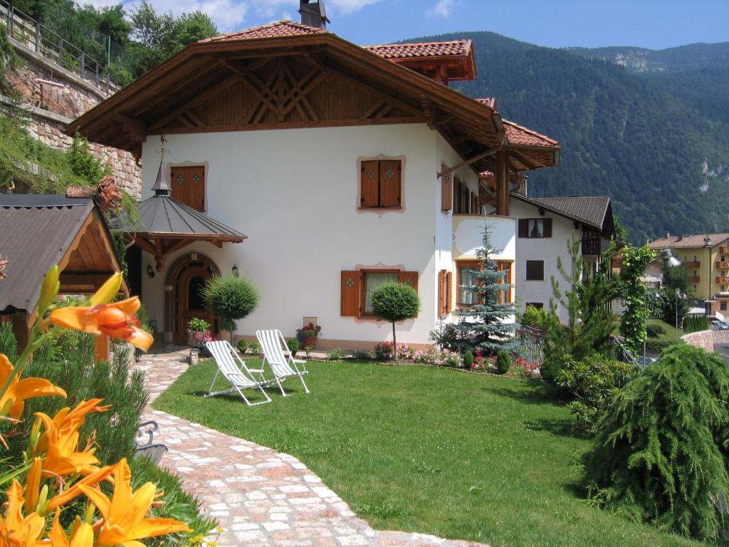 une maison avec une pelouse et des chaises devant elle dans l'établissement Appartamenti Donini Alfredo, à Molveno