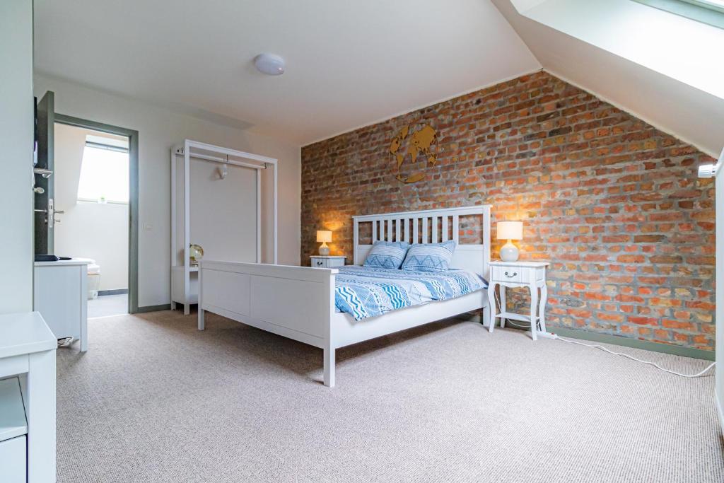 a bedroom with a brick accent wall and a bed at Suite Leopold in Bruges