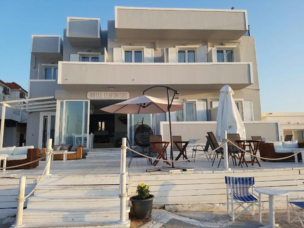 a building with tables and chairs and an umbrella at Hotel Elafonisos in Elafonisos