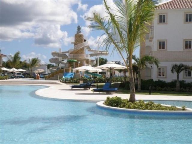 un complejo con piscina con sillas y un edificio en Appartamenti in Cadaques Caribe, en Bayahibe
