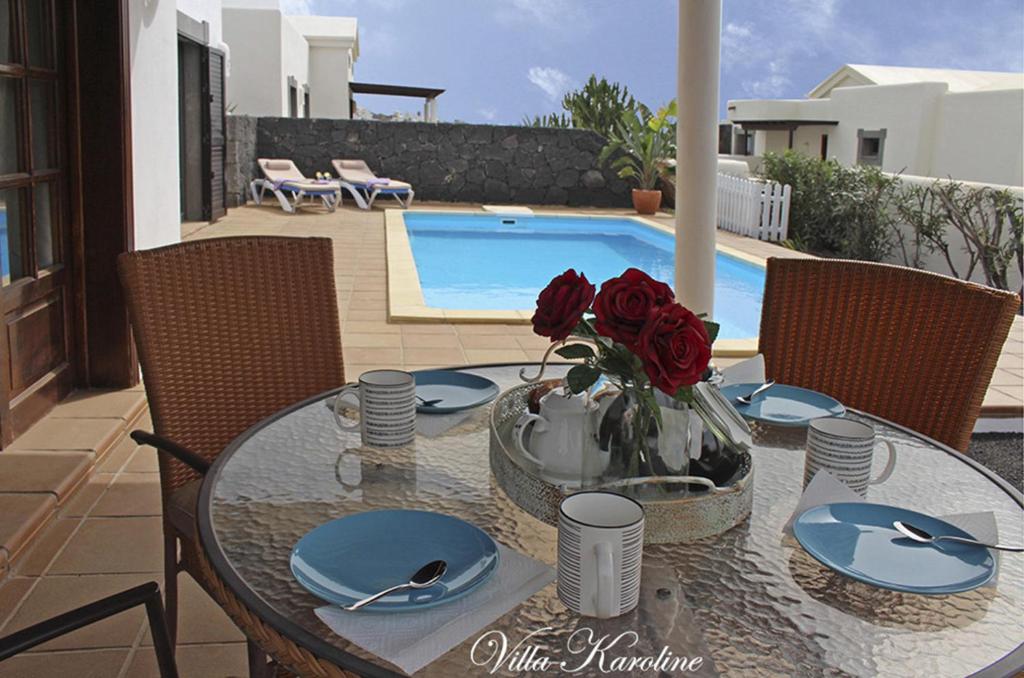 uma mesa de jantar com rosas num vaso num pátio em Villa Karoline em Playa Blanca
