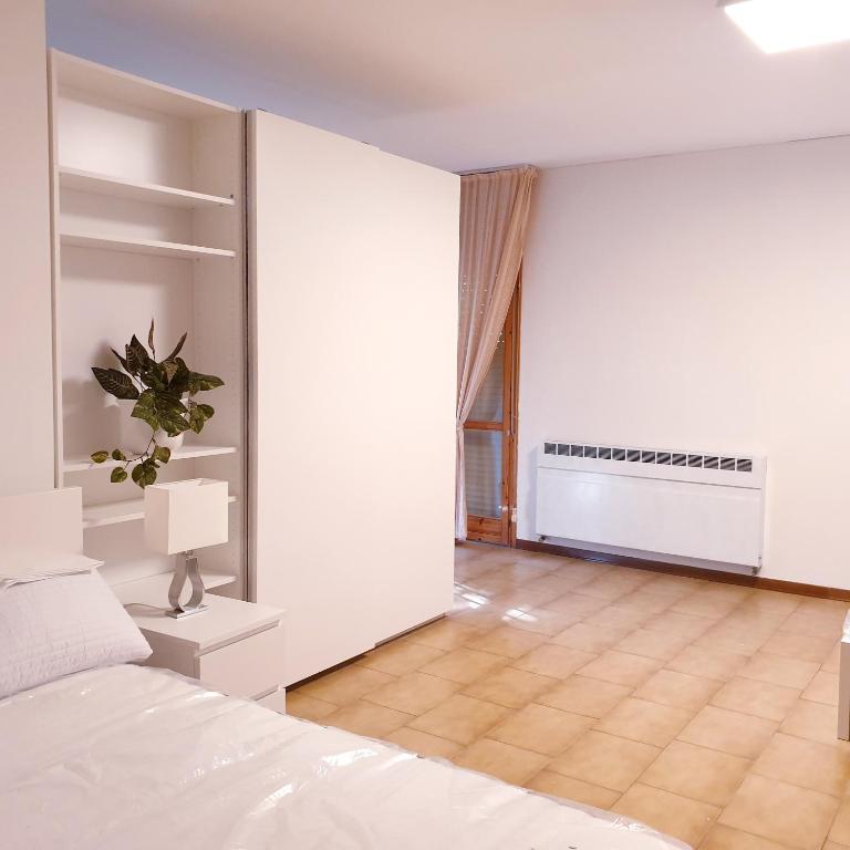 a bedroom with white walls and a bed and a window at Hotel Paradiso Dépendance in Altedo