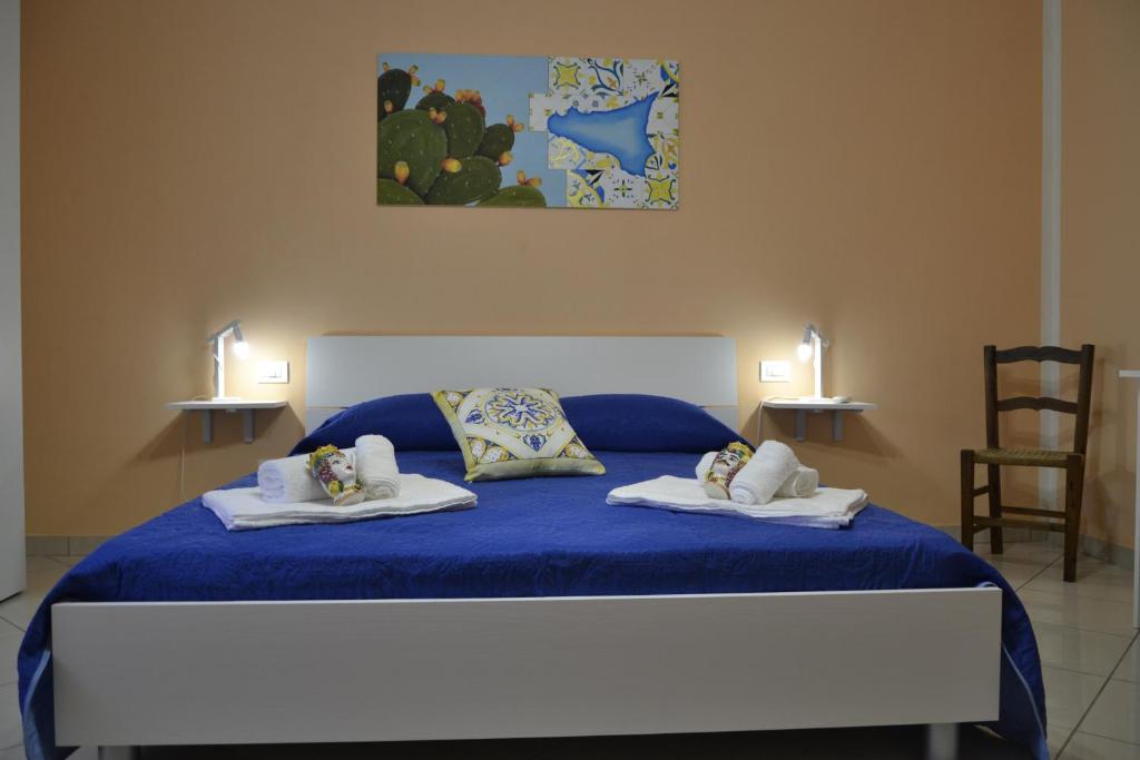 Un dormitorio con una cama azul con toallas. en I Colori della Sicilia, en Valderice