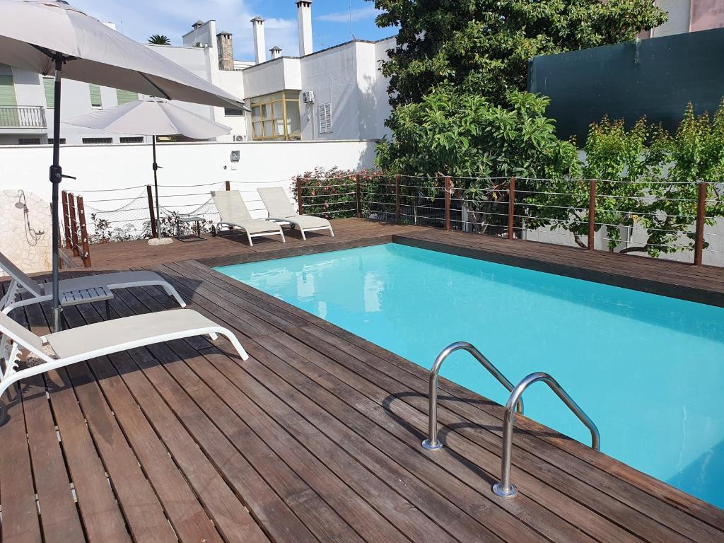 a swimming pool with chairs and an umbrella on a deck at Il Giardino Di Flora in Lecce