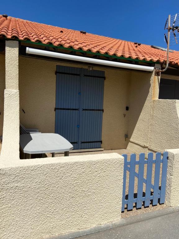 a house with a white table and a blue fence at Maison Eden en village Naturiste in Leucate