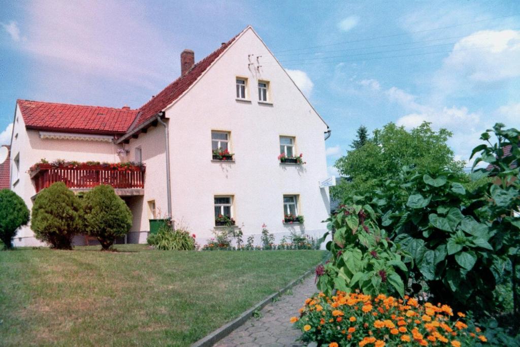 duży biały dom z kwiatami przed nim w obiekcie Pension Annelie w mieście Schullwitz