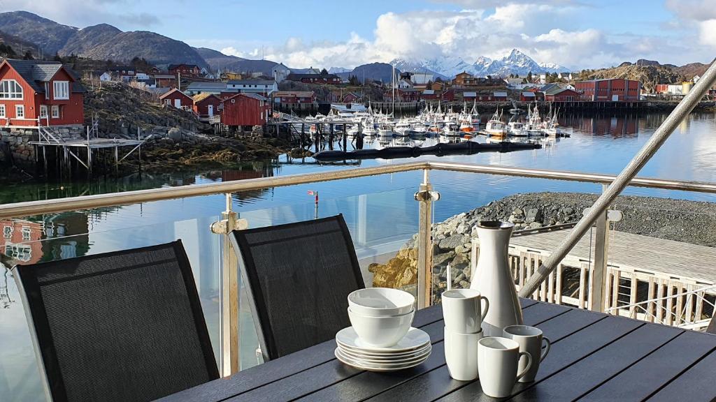 a table with plates and cups on a balcony with a marina at Lofoten Seaside in Ballstad
