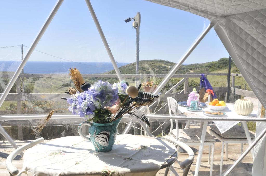 a vase of flowers on a table on a balcony at Agriturismo Glamping Erbe Matte in SantʼAntìoco