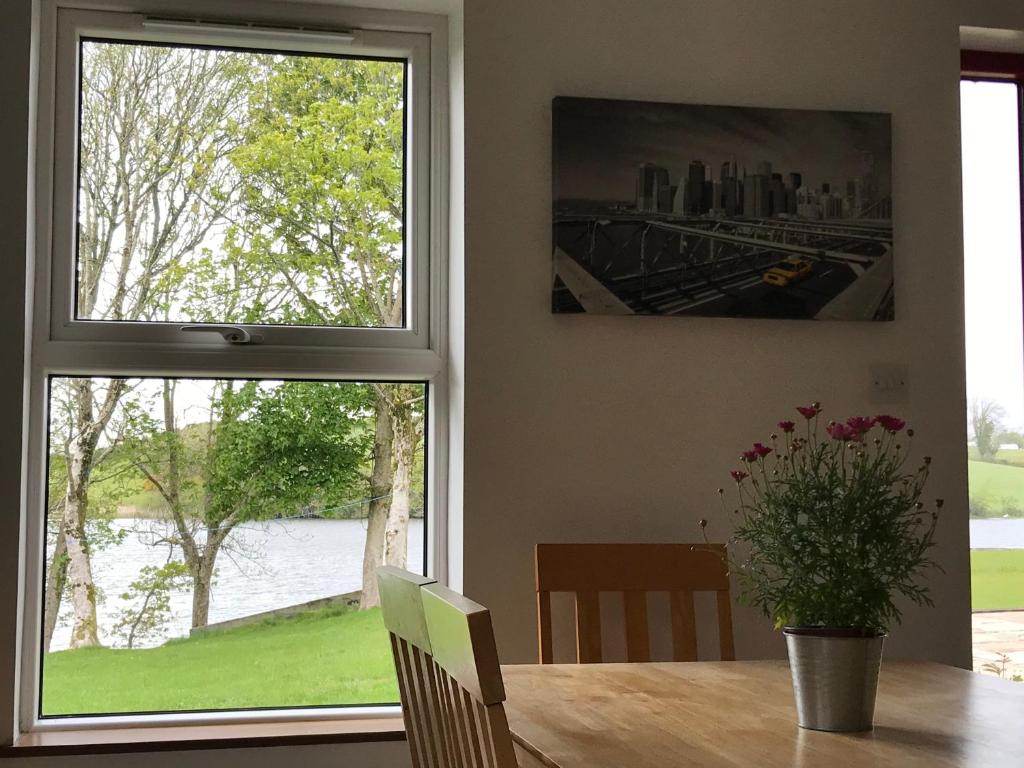a dining room with a table and two windows at Lakeside Lookout Bantry in Cork