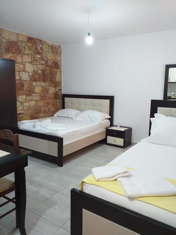 a bedroom with two beds and a brick wall at Grand Seaview Apartments in Ksamil