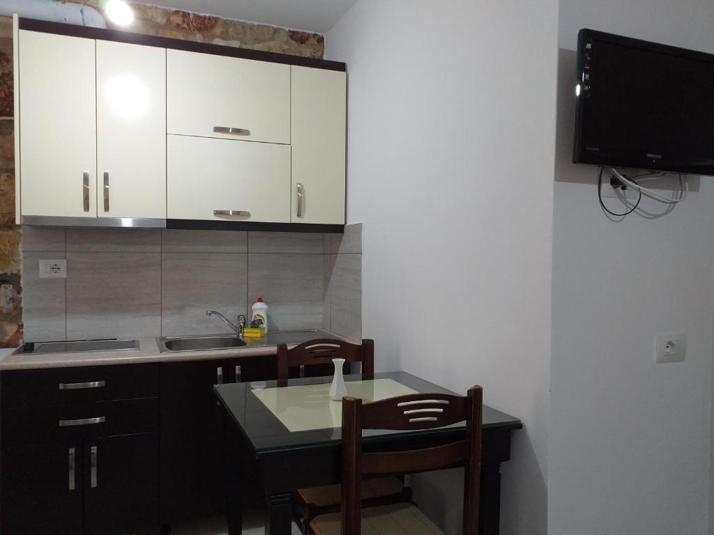 a kitchen with a table and chairs and a tv at Grand Seaview Apartments in Ksamil
