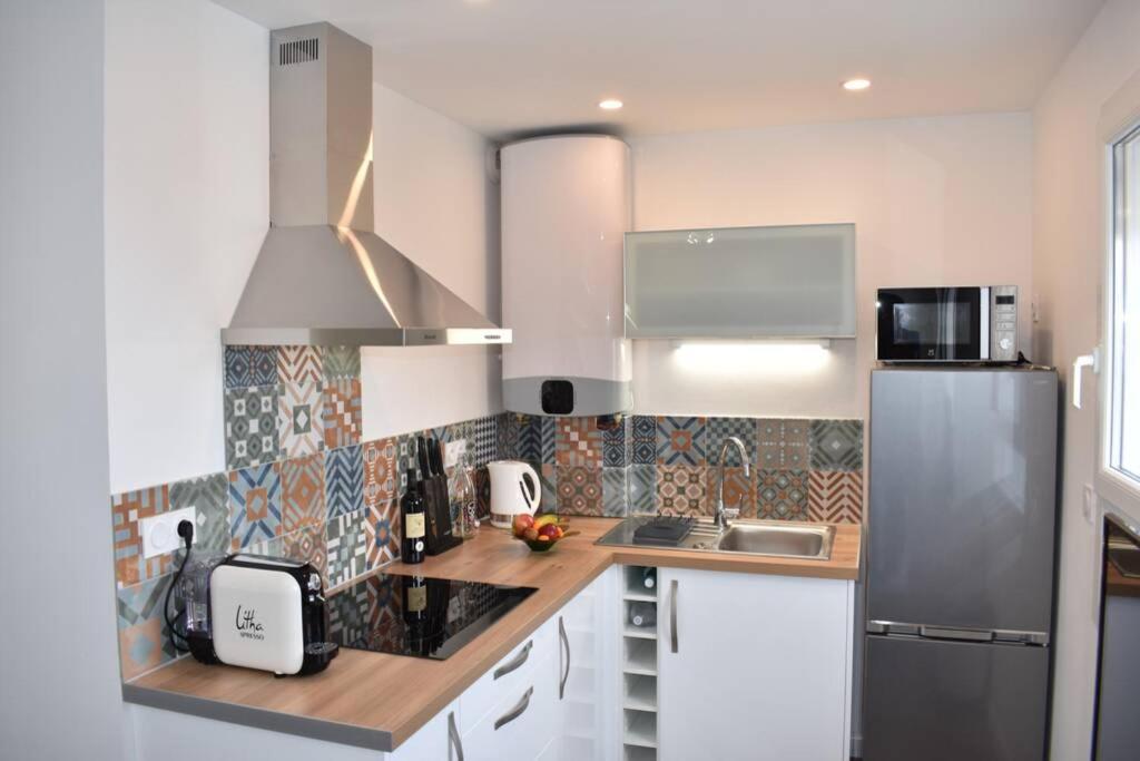 une cuisine avec un réfrigérateur en acier inoxydable et des armoires blanches dans l'établissement Confort et calme au sud de Bastia, à Bastia