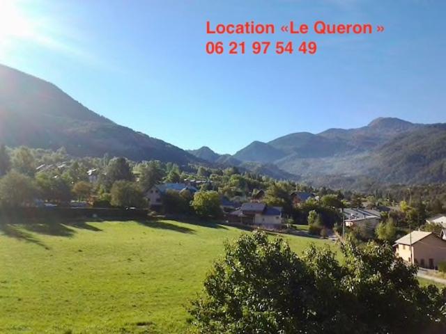 a view of a green field with mountains in the background at Location Le Queron in Guillestre
