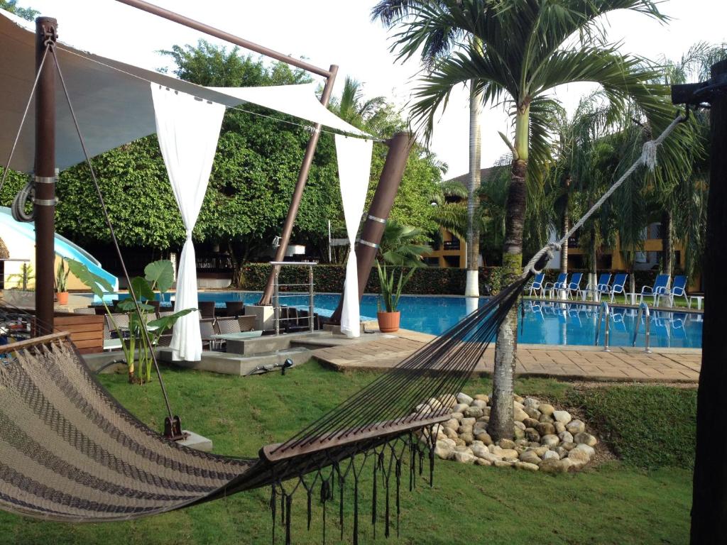 a hammock in front of a swimming pool at Hotel Ciudad Real Palenque in Palenque