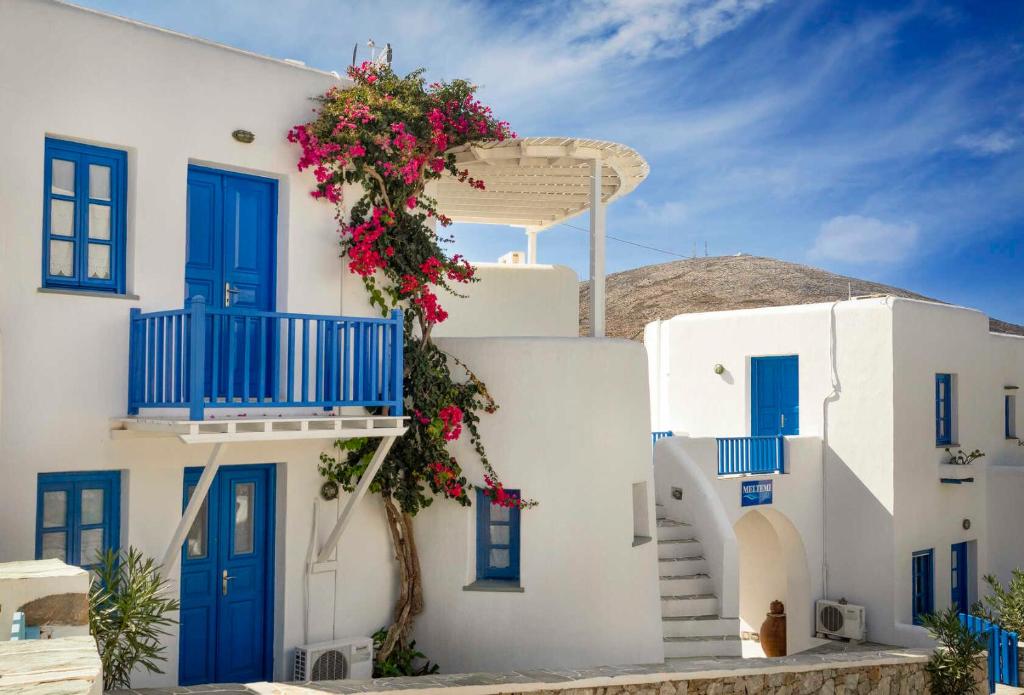 a white building with blue doors and flowers on it at Meltemi in Chora Folegandros