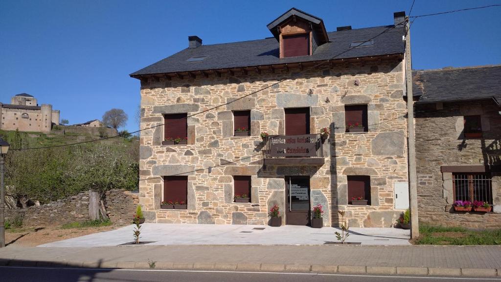 een groot stenen gebouw met een zwart dak bij APARTAMENTOS TURISTICOS LAS CANDELAS in Puebla de Sanabria