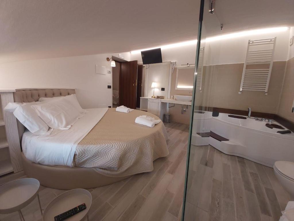 ein Schlafzimmer mit einem Bett und ein Badezimmer mit einer Badewanne in der Unterkunft Resort la dimora Maiale brado di Norcia in Norcia
