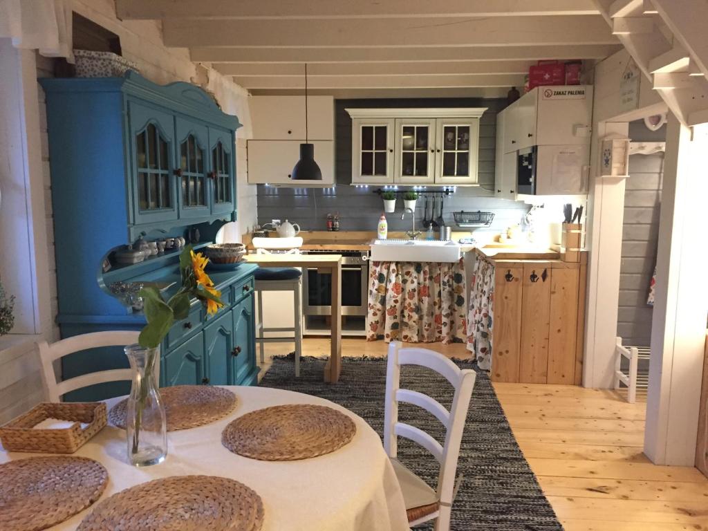 a kitchen with blue cabinets and a table with chairs at Domki Mojo Miodno Checz Sasino in Sasino