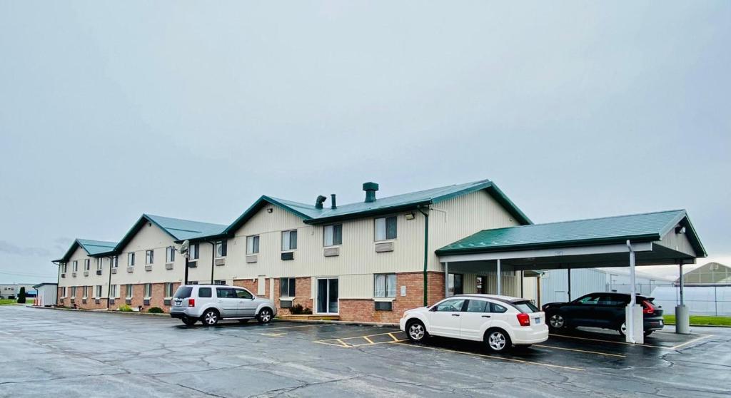 zwei Autos auf einem Parkplatz vor einem Gebäude geparkt in der Unterkunft wallaceburg inn in Wallaceburg