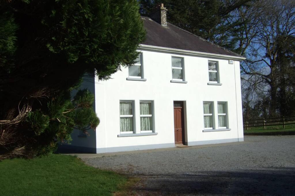 a white house with a red door at Sporting Lodge Shanagolden in Limerick