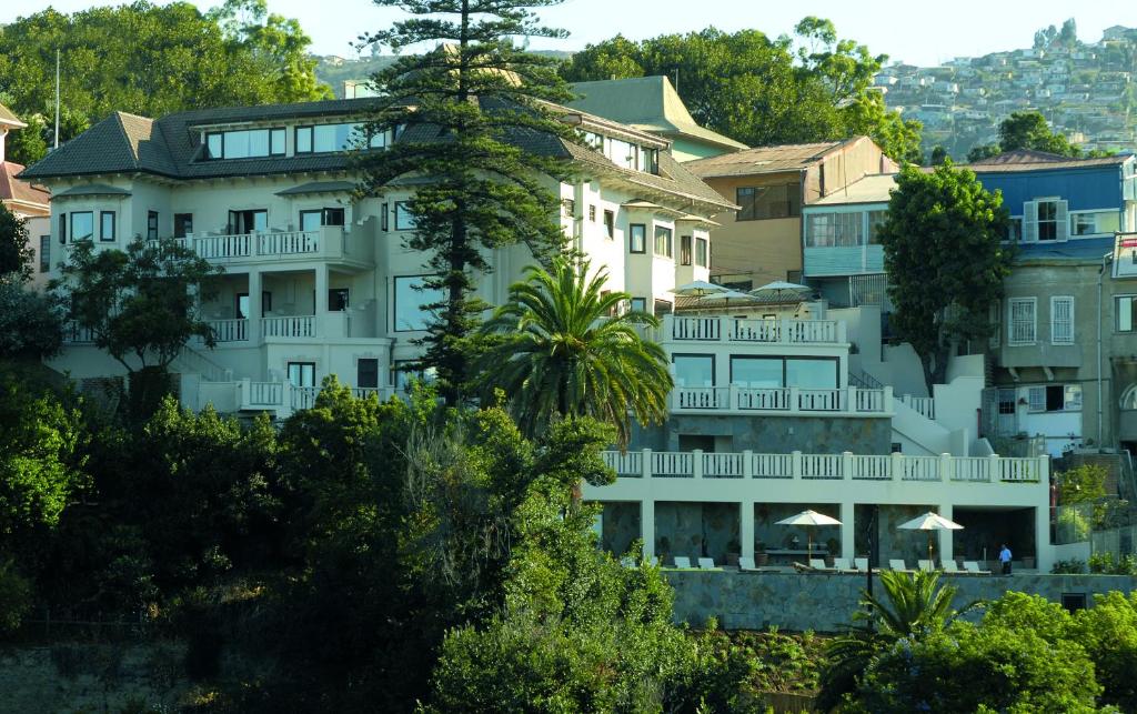 un grand bâtiment blanc avec des arbres devant lui dans l'établissement Hotel Casa Higueras, à Valparaíso